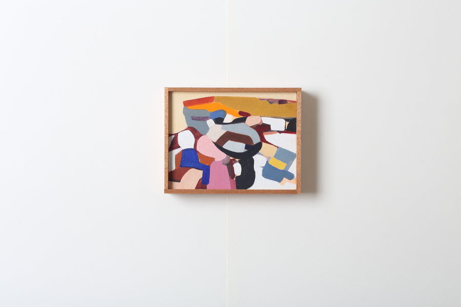 Abstract art piece with colorful geometric shapes in a wooden frame on a white wall