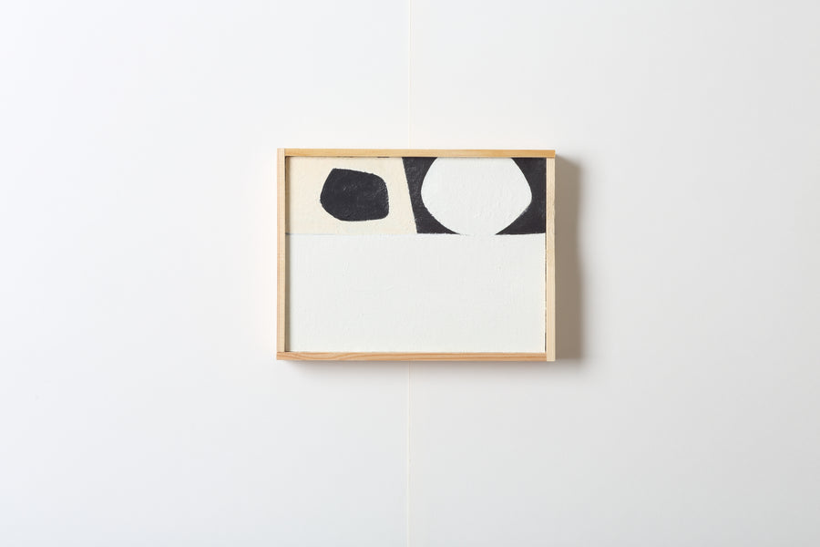 Framed abstract artwork with geometric black and white design on a light gray background