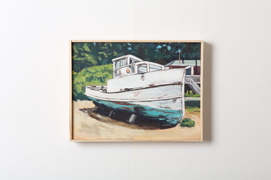 Framed painting of a rustic white and blue bottomed boat on a beach with a trees and a red building with a white staircase in the background