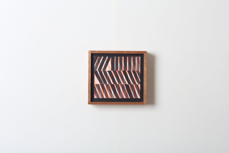 Abstract art piece with uniform shapes in a wooden frame on a white wall